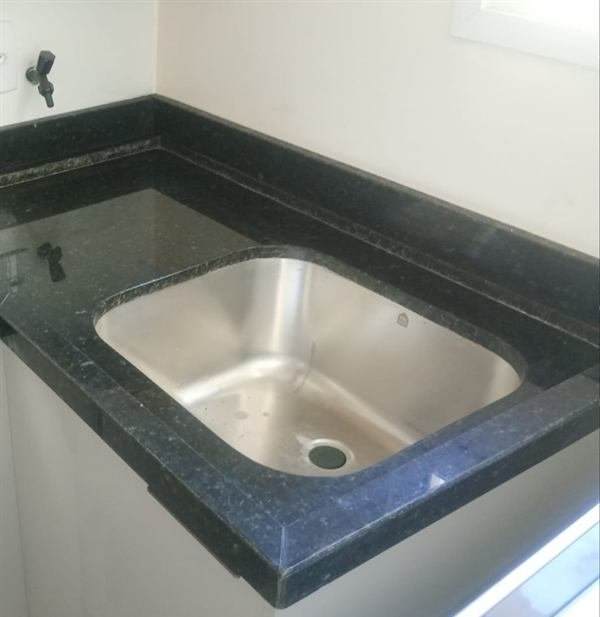 Detalhe de bancada em pedra escura com cuba inox