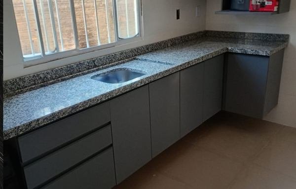 Cozinha em L com bancada em pedra cinza e armários escuros