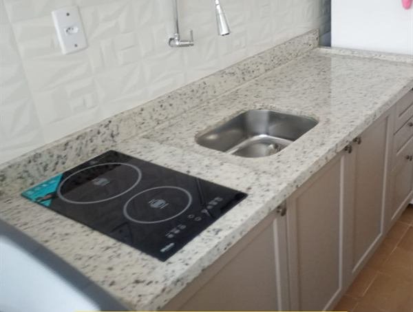 Bancada de cozinha em pedra clara com cooktop e cuba
